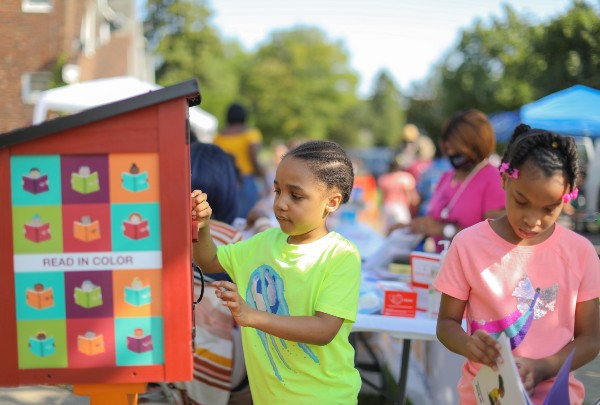 Children selecting books from a Little Free Library book-sharing box