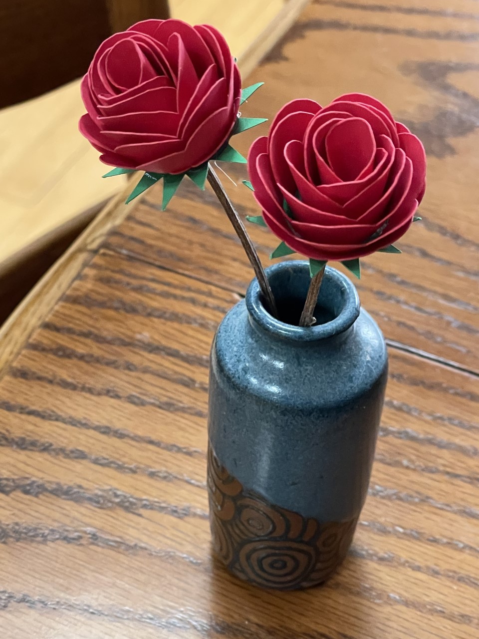 Photo of two red laser cut roses in a blue glass vase