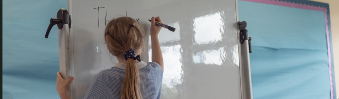 a pupil writing on a whiteboard