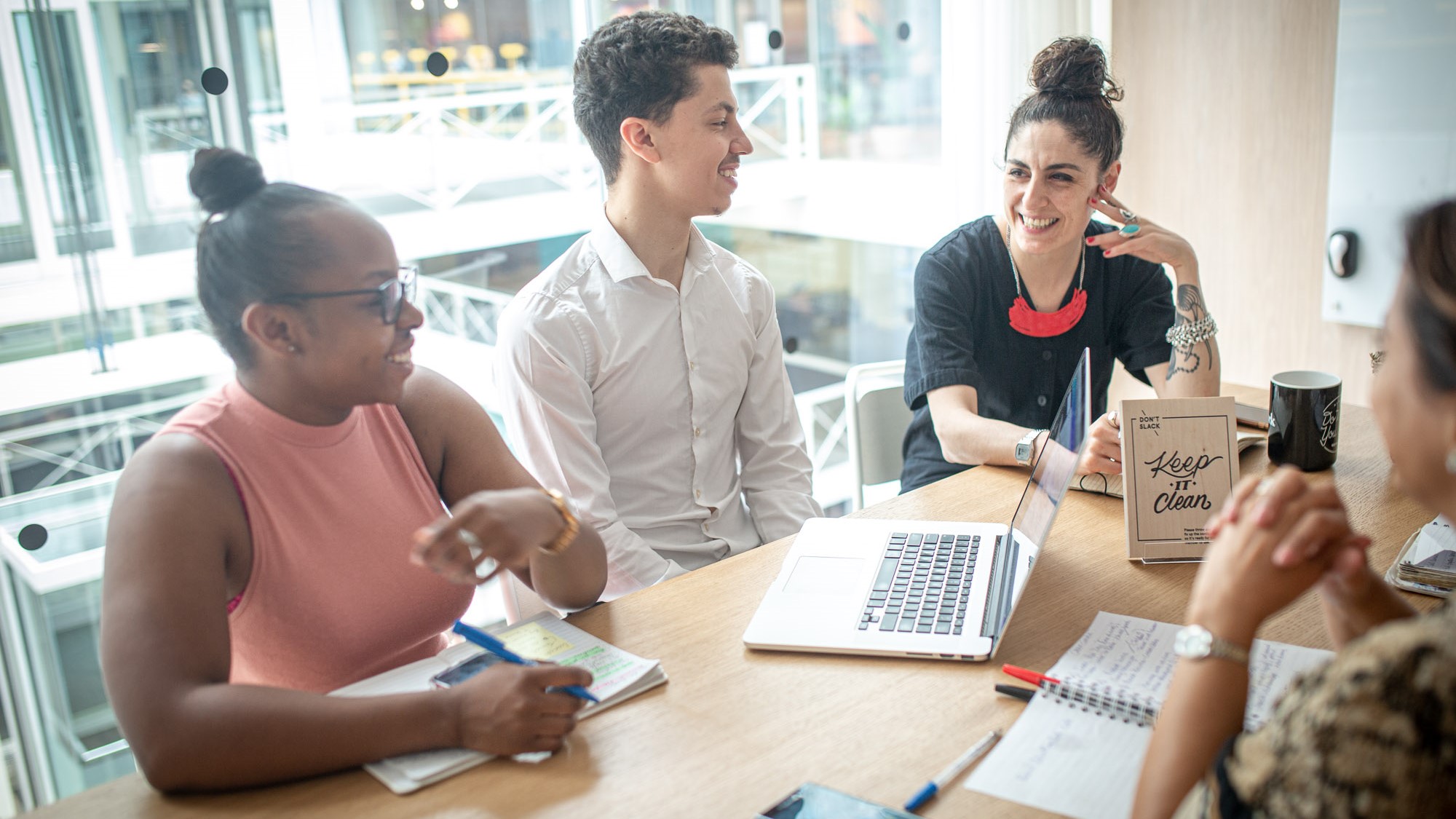Three people sit at a table talking and smiling