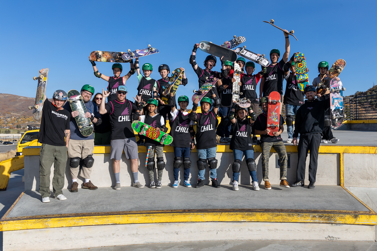 A group of youth in chill jersey's proudly hold up skateboards celebrating